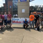 Picture of a group of students in Atlanta, Georgia, standing around a banner advertising the Atlanta Maker Faire