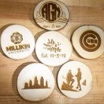 Picture of circular pieces of wood, each with a different image etched into it with a laser cutter, sitting on a table
