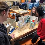 Picture of three students sitting around a table in the Innovation and Collaboration Studio, working on a project