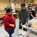Picture of three students using the hand sander to sand wood in the Innovation and Collaboration Studio