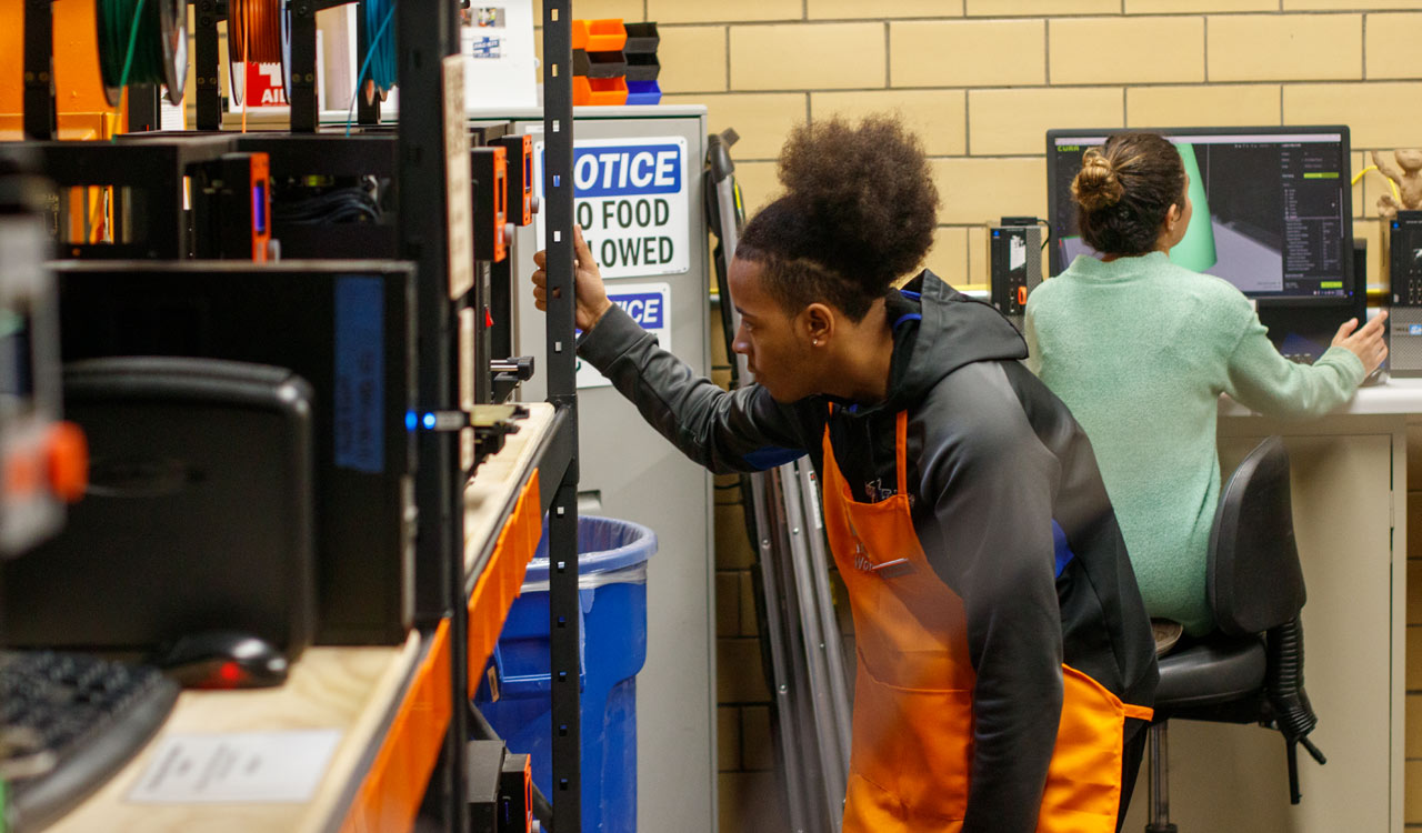 Student Checks on 3D Printer in Lab